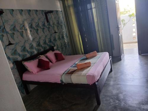 a bed in a room with pink pillows on it at Kentz villa in Arugam Bay