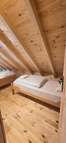 a bed in a room with a wooden ceiling at Bungalows Prokletije in Gusinje