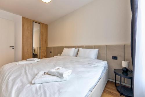 a bedroom with a white bed with towels on it at Apartmani Aurora Zlatibor in Zlatibor
