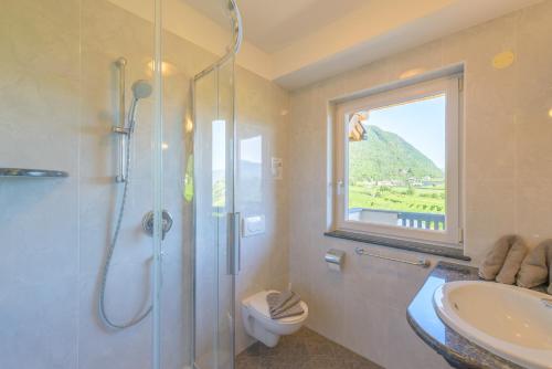 a bathroom with a shower and a sink and a window at Garni Hotel Peterlinhof in Caldaro