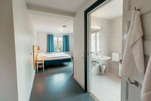 a bathroom with a sink and a bed in a room at Falstadsenteret Hotell - Museum, minnested og senter for menneskerettigheter in Levanger