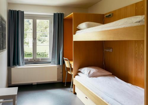 a bedroom with two bunk beds and a window at Falstadsenteret Hotell - Museum, minnested og senter for menneskerettigheter in Levanger