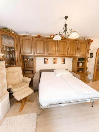 a bedroom with a bed and a chair and cabinets at Ferienwohnung Hinterthal in Hinterthal