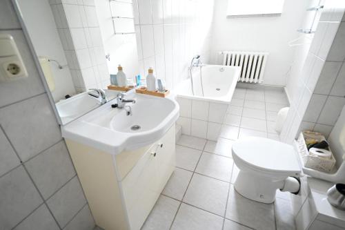 a white bathroom with a sink and a toilet at Hotel Hermannshöhle in Elbingerode