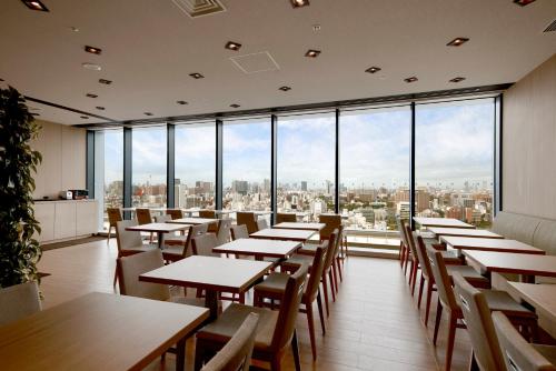 a restaurant with tables and chairs and large windows at Hotel Crown Hills Ueno Premier in Tokyo