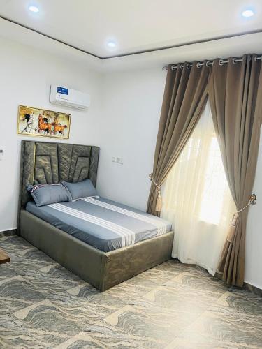 a bedroom with a bed and a window with curtains at DAS Apartments Lugbe in Abuja