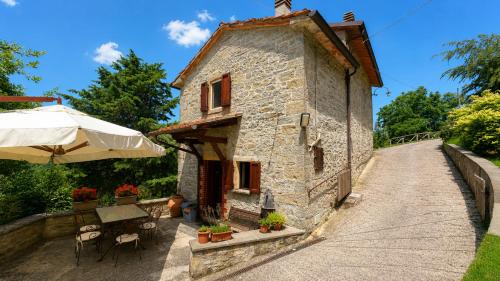 ein kleines Steinhaus mit einem Tisch und einem Sonnenschirm in der Unterkunft Poet's Rest in Pieve Santo Stefano