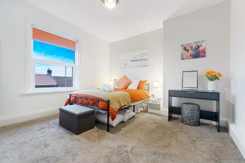 a bedroom with a bed and a desk and a window at Cosy 2BR Apartment Sleeps 4 by Stay With Us in Hawthorn