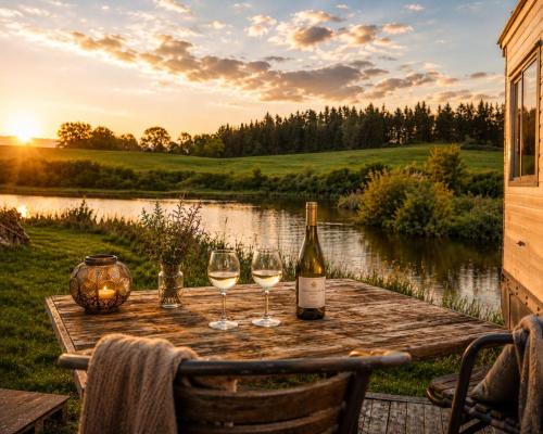 a table with wine glasses and a bottle of wine at Krusmølle Glamping in Aabenraa