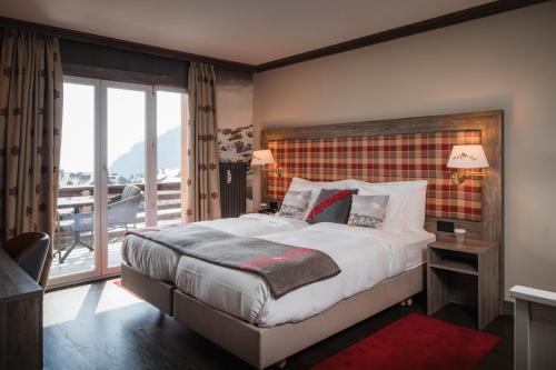 a bedroom with a large bed and a balcony at Hotel Bristol Verbier in Verbier