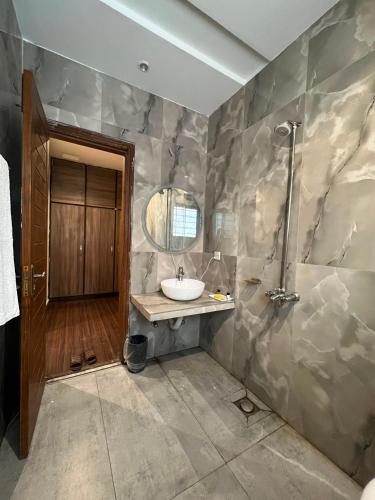 a bathroom with a sink and a shower at Shelton Hotel Gulberg in Lahore