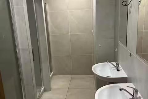 a white bathroom with a shower and a sink at Meštiansky dom in Stupava