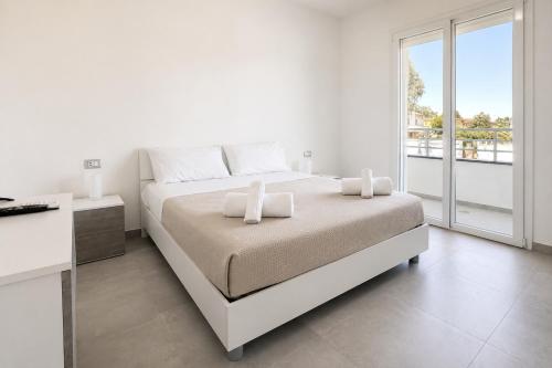 a white bedroom with a large bed and a window at Pierre Palace in Isola Sacra