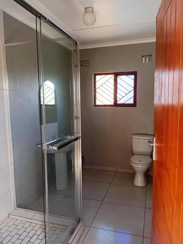 a bathroom with a glass shower and a toilet at Radies Bed and Breakfast in Cofimvaba