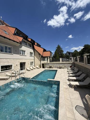 a swimming pool with lounge chairs next to a building at Divski Resort in Divčibare
