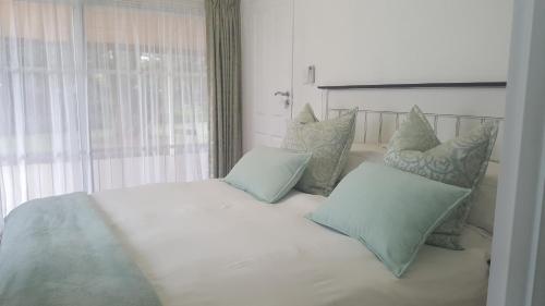 a bedroom with a white bed with pillows and a window at Spring Acres Guesthouse in Nelspruit