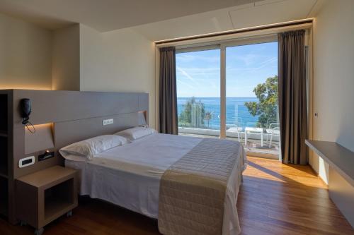 ein Schlafzimmer mit einem Bett und einem großen Fenster in der Unterkunft Hotel Le Roi in Varraze