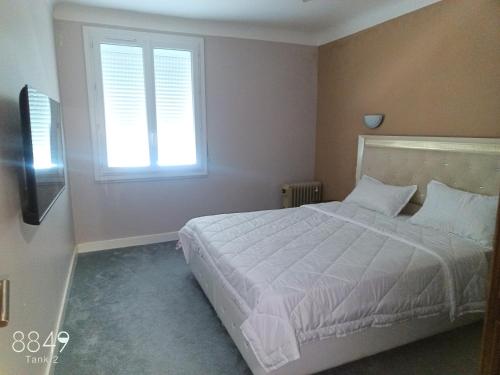 a bedroom with a white bed and a window at Grand appartement familiale in Issoire