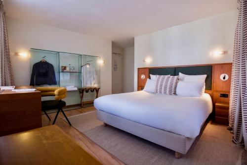 a bedroom with a large white bed and a desk at Hôtel La Pérouse in Nantes