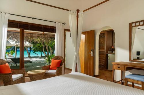 a bedroom with a bed and a view of a pool at Niva Kuramathi Maldives in Rasdhoo