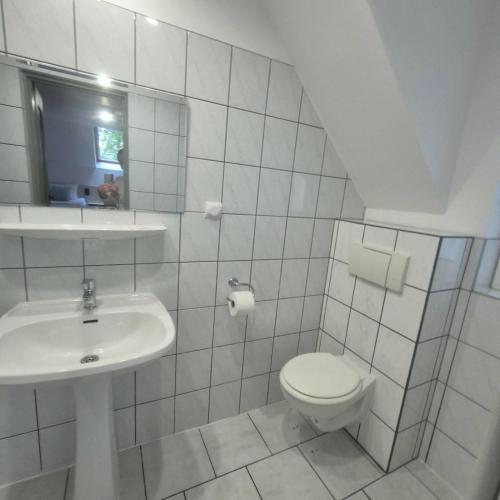 a white bathroom with a toilet and a sink at Willa Na Deptaku in Pobierowo