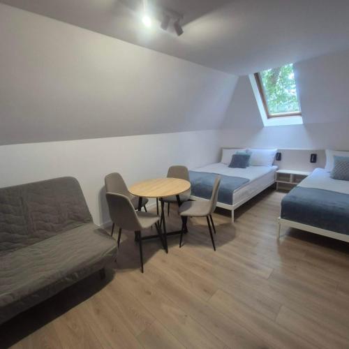 a room with a bed and a table and chairs at Willa Na Deptaku in Pobierowo