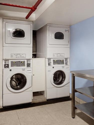 a laundry room with three washing machines and a table at Central Park West Hostel in New York