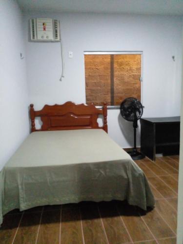 a bedroom with a bed and a window with a fan at Casa veraneio in Soure