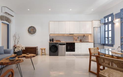 a kitchen and living room with white cabinets and a table at Vivian Dio Choria Tinos in Dhió Kkhoriá