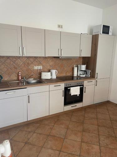 a kitchen with white cabinets and a stove top oven at Ferienwohnung Jach in Triglitz