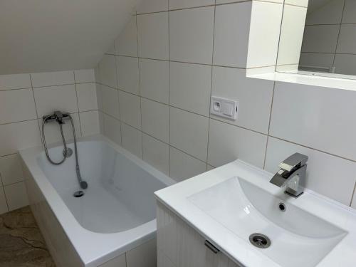 a white bathroom with a sink and a bath tub at Harrachovský Chalet Gryf u sjezdovky in Ryžoviště