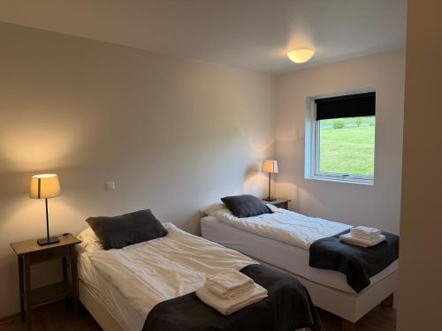zwei Betten in einem Zimmer mit zwei Lampen und einem Fenster in der Unterkunft Stöð-INN in Stöðvarfjörður