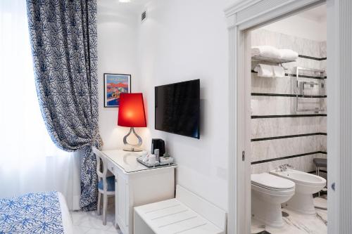 a bathroom with a toilet and a desk with a lamp at La Ciliegina Lifestyle Hotel in Naples