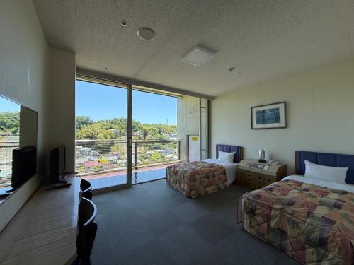 a hotel room with two beds and a large window at WELLNESS PARK IWAKI Iwaki Yuttarikan in Iwaki