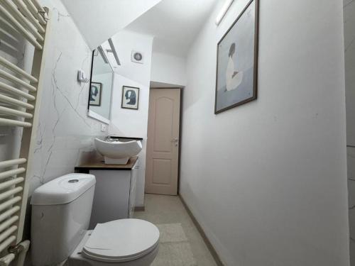 a white bathroom with a toilet and a sink at Cozy Central Apartament II in Bacău