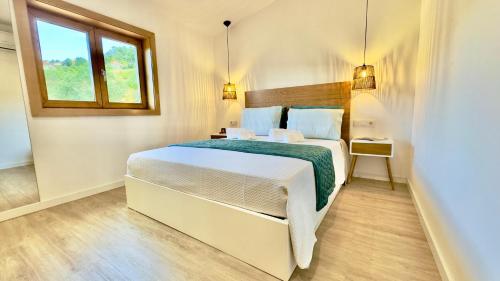 a bedroom with a large white bed with a window at Refúgio do Espigueiro in Amarante
