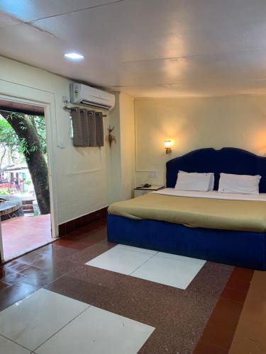 a bedroom with a bed and a door to a patio at Horseland Hotel & Mountain Spa in Matheran