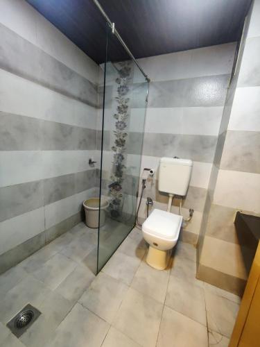 a bathroom with a toilet and a glass shower at Horseland Hotel & Mountain Spa in Matheran