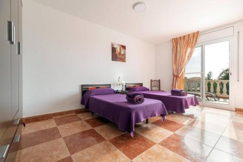 two beds in a room with a large window at Vista Cunit es una gran casa con piscina, barbacoa in Cubelles