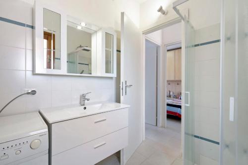 a white bathroom with a sink and a mirror at Casa Serena in San Teodoro