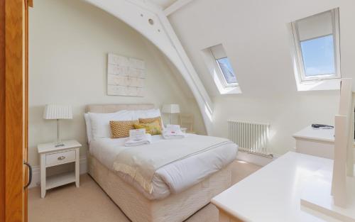 a white bedroom with a bed and two windows at 5 Old School Mews Shanklin in Shanklin