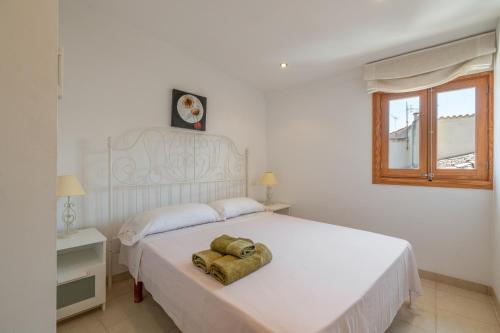 a white bedroom with a bed with a towel on it at Casa Nord in El Port de la Selva