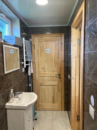 a bathroom with a sink and a wooden door at Atostogų namelis Stebuliuose in Stebuliai