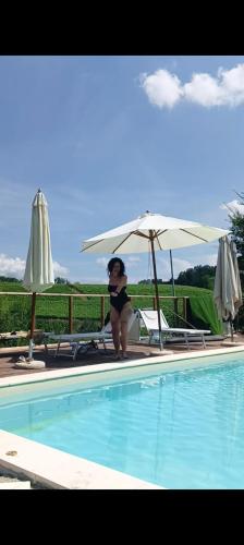 a woman in a bikini standing next to a swimming pool at Arco Dei Nobili in Monforte dʼAlba