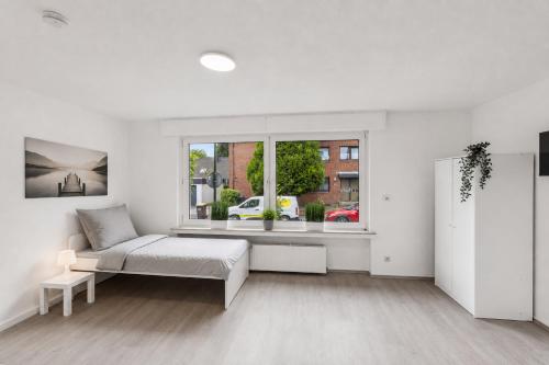 a white bedroom with a bed and a window at NM living Lünen VII in Lünen