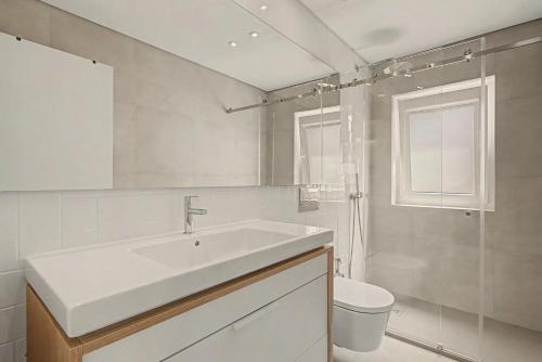 a white bathroom with a sink and a toilet at Trafaria Bliss in Trafaria