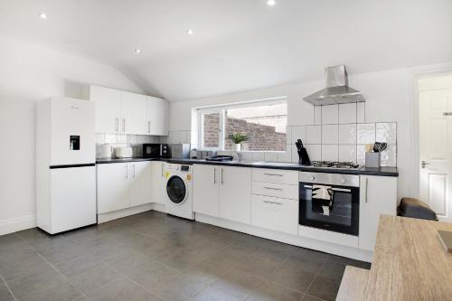 a kitchen with white cabinets and a washer and dryer at Stylish 2BR House in Ashington by Stay With Us in Ashington