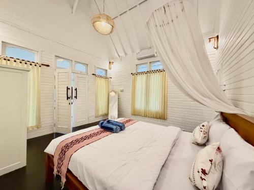a bedroom with a large bed in a room with windows at Bronze Bungalows in Gili Meno