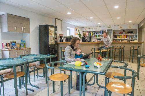 a woman holding a baby sitting at a table in a restaurant at camping du haut des bluches in La Bresse
