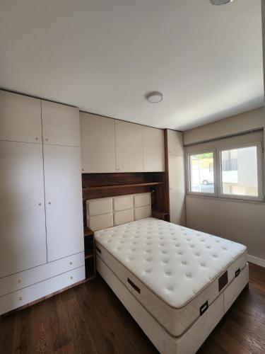 a bedroom with a bed and cabinets and a window at Apartman Bloom 6 in Tivat